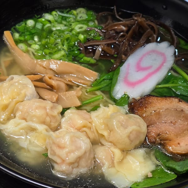 Close-up of Momoyama Ramen with wontons, pork, bamboo shoots, scallions, and a slice of narutomaki.