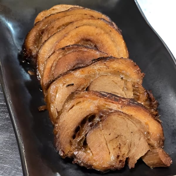 Momoyama Ramen's chashu pork, thinly sliced and arranged on a black rectangular plate.