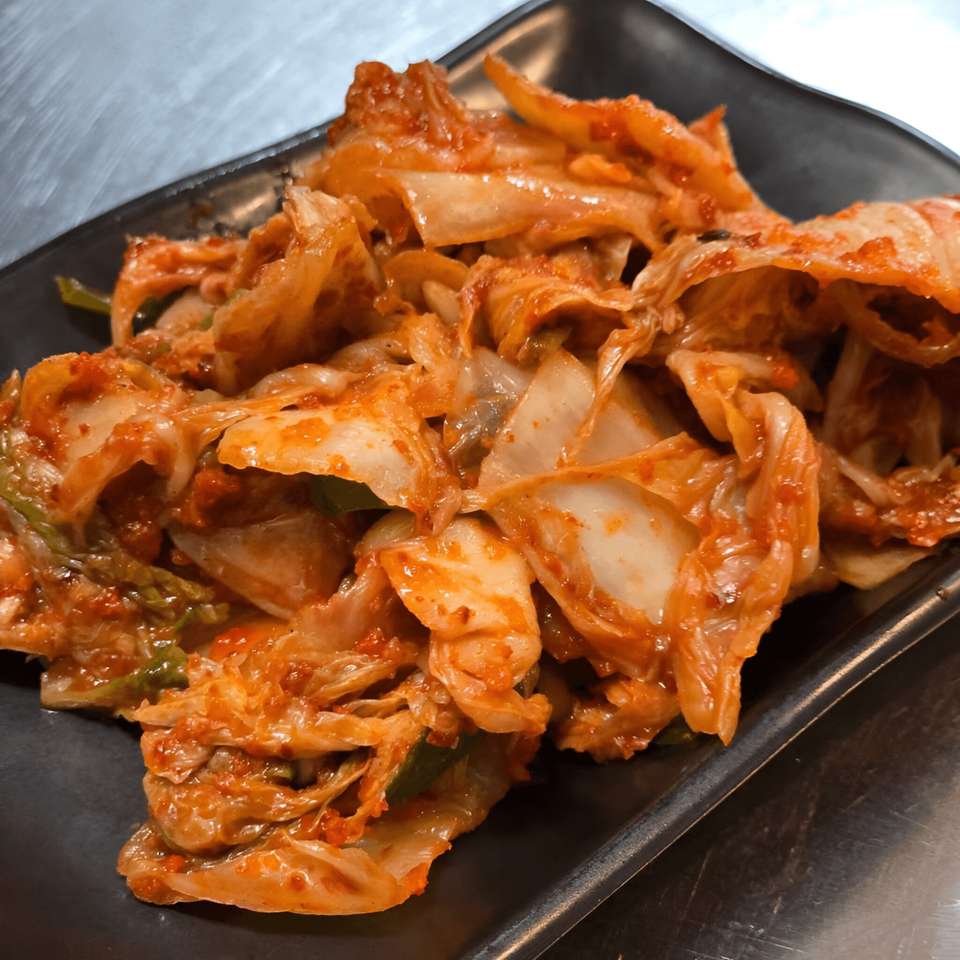 A close-up of Momoyama Ramen & Hawaiian BBQ's spicy kimchi on a black plate.