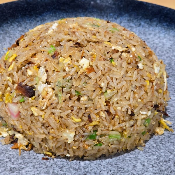A close-up of a mound of Momoyama Ramen & Hawaiian BBQ fried rice with egg and vegetables.