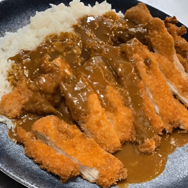 Momoyama Ramen & Hawaiian BBQ's chicken katsu curry with white rice on a dark plate.